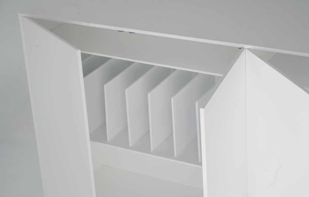 A close-up of the interior of a minimalist white sideboard. The doors are open, revealing several vertical dividers within one of the compartments.