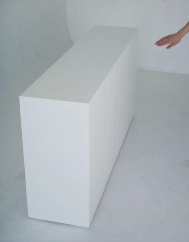 A profile of a minimalist white sideboard. The front features four closed doors, each flush with the overall structure.