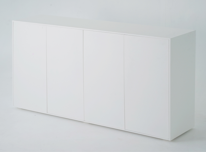 A wide shot of a minimalist white sideboard. The front features four closed doors, each flush with the overall structure. 