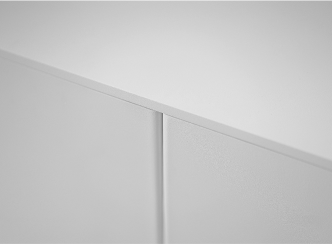 An angled close-up detail of the minimal spacing between the doors of a white sideboard.