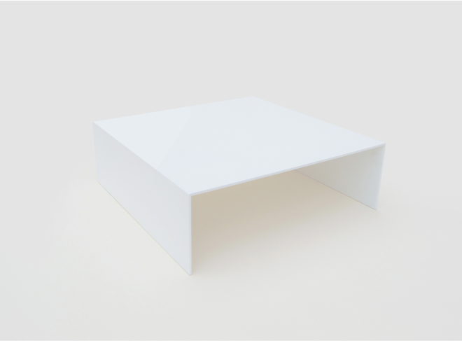 A wide overhead angle of a white rectangular table with minimalist design. Bent at the edges to form a sharp U-shape.