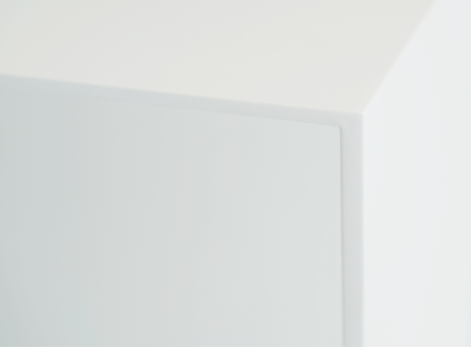 A detail of an eased edge on the white table that forms from the thinner top moving to a thicker leg.
